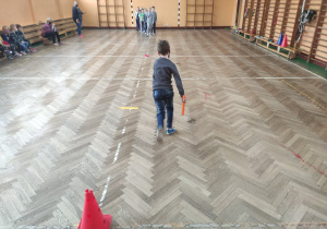 Chłopiec biegnie na linie mety, w tle uczniowie jego klasy